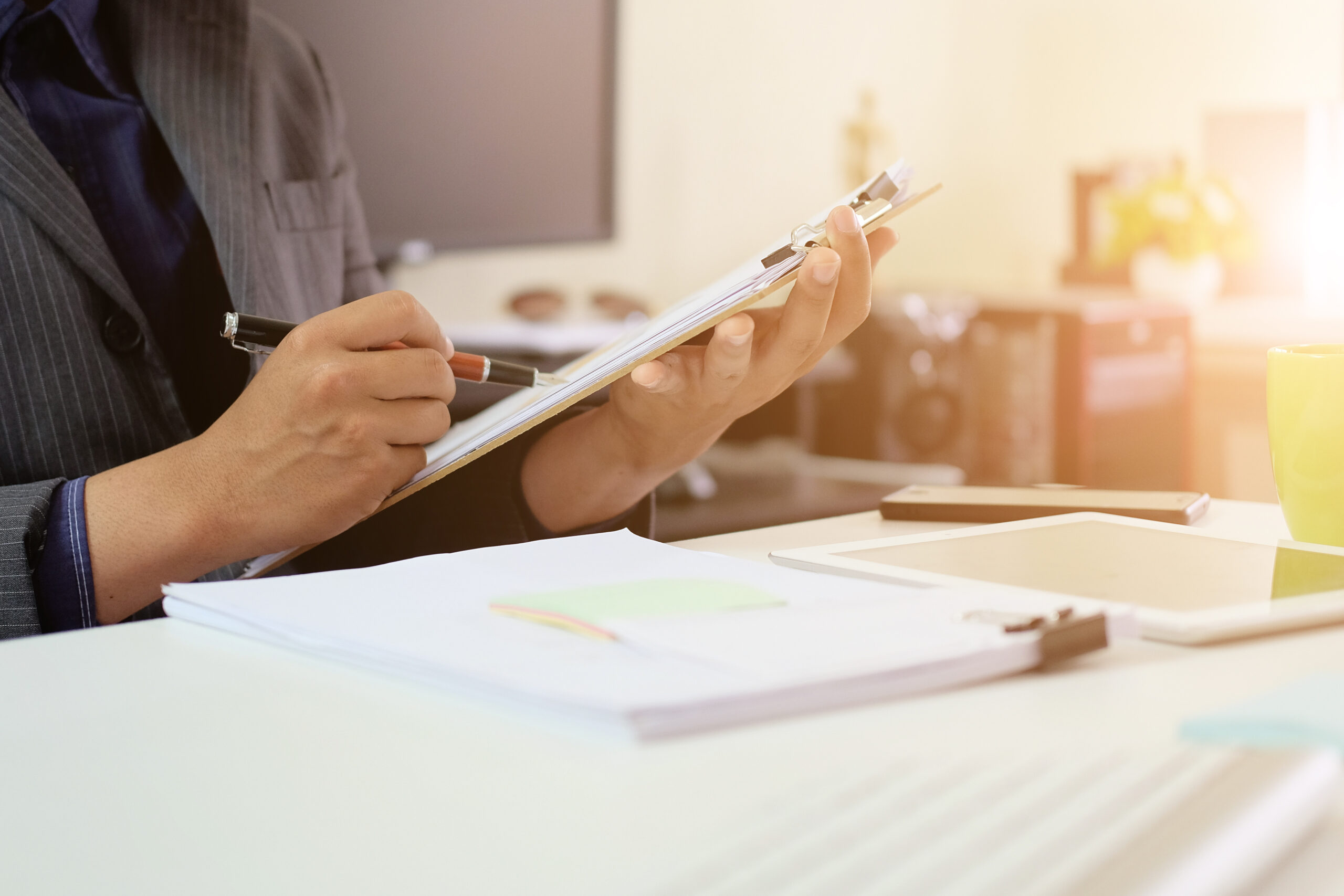 A person filling out an audit checklist on a clipboard at a desk, representing the compliance review process for PIPEDA requirements