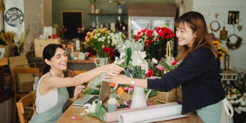 Two small business owners in aprons working together at a laptop in their retail shop