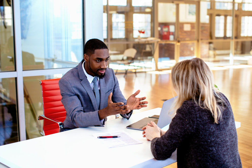 Business owner questioning a managed IT provider across a meeting table, with a written proposal between them