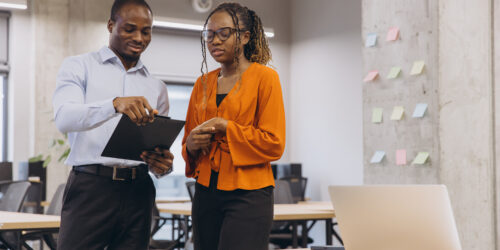 Two colleagues working through a plan with a clipboard and sticky notes, deciding how the business keeps running during an outage