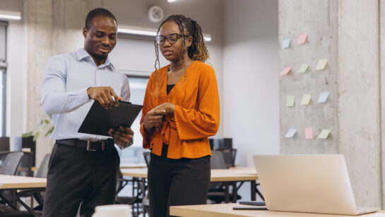 Two colleagues working through a plan with a clipboard and sticky notes, deciding how the business keeps running during an outage