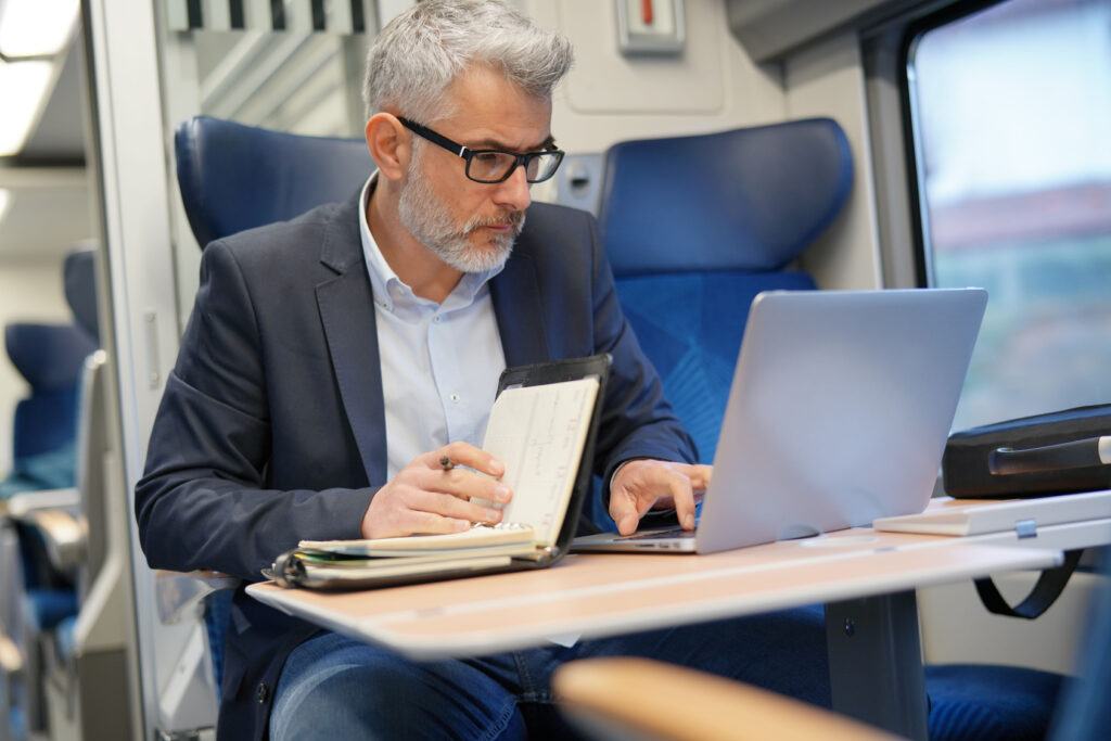 Professional working on a laptop while commuting by train, reaching company files stored in the cloud