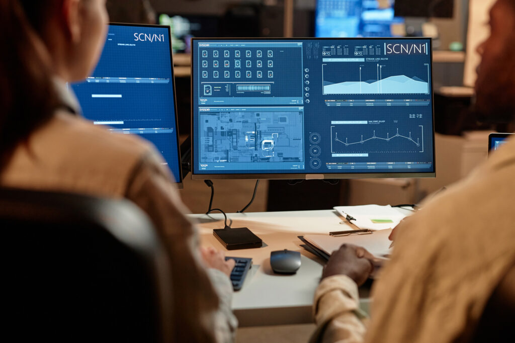 Two IT staff reviewing system data on a monitor together, internal IT working alongside an outside partner