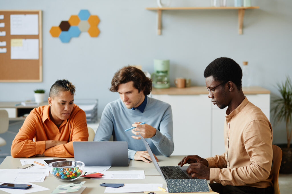 Internal IT staff and outside IT specialists working side by side on laptops during a co-managed IT project