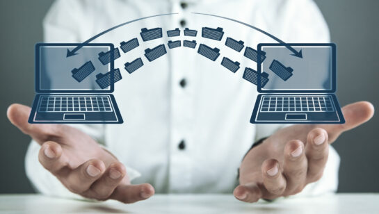 Two laptops side by side with files moving between them, representing the data and system handover when a business switches IT providers