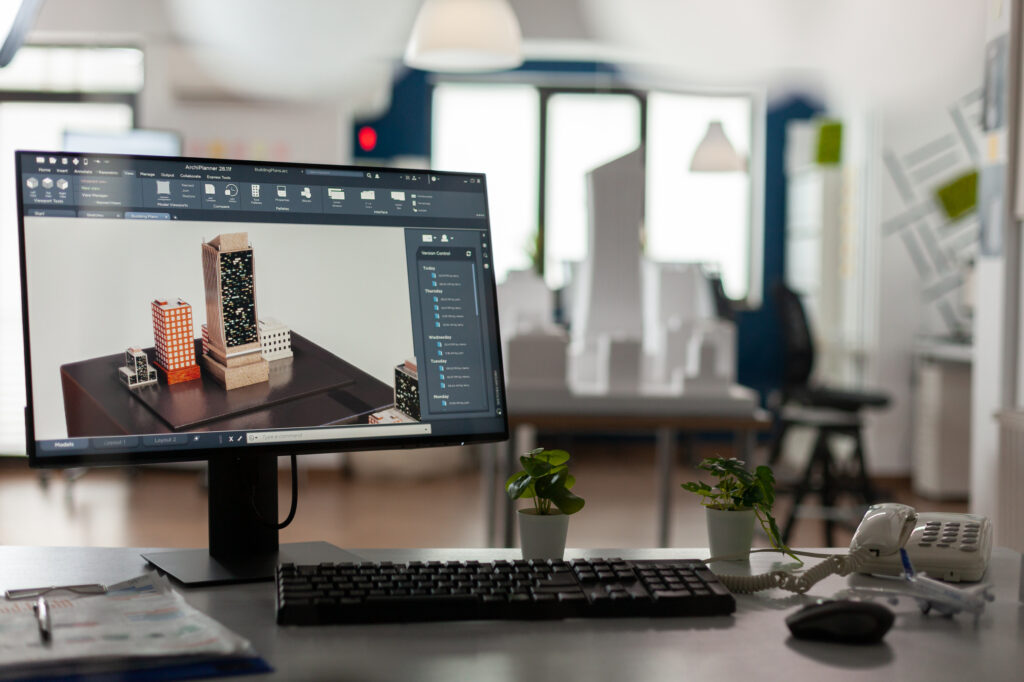 Architecture studio workstation showing a 3D render of a building complex on the monitor