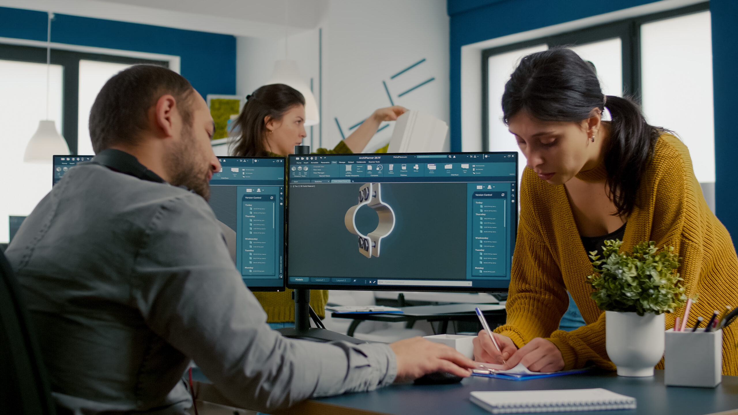 Engineering team reviewing a 3D CAD model on dual monitors at a design workstation