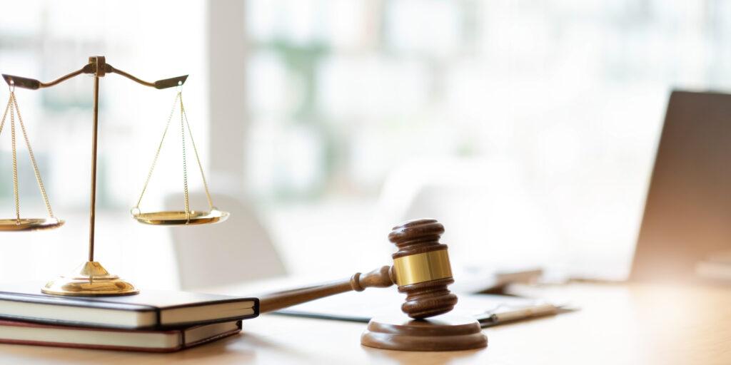 Lawyer and client reviewing papers on a desk beside brass scales of justice, representing a law firm weighing its IT support budget