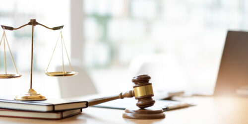 Lawyer and client reviewing papers on a desk beside brass scales of justice, representing a law firm weighing its IT support budget