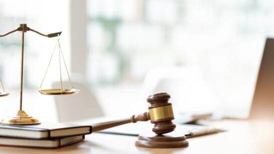 Lawyer and client reviewing papers on a desk beside brass scales of justice, representing a law firm weighing its IT support budget