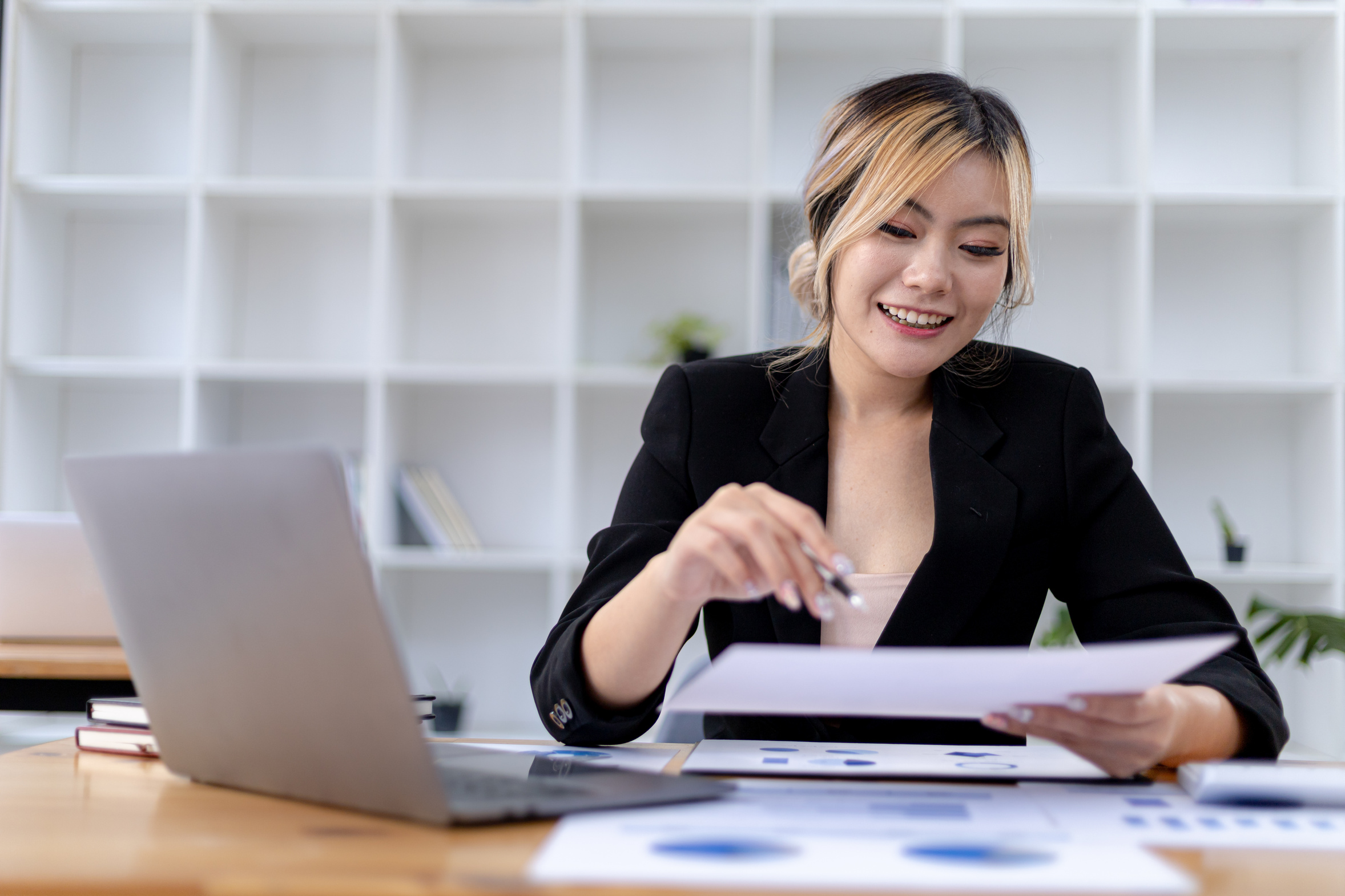 Business owner reviewing financial documents at her desk while planning the monthly IT budget