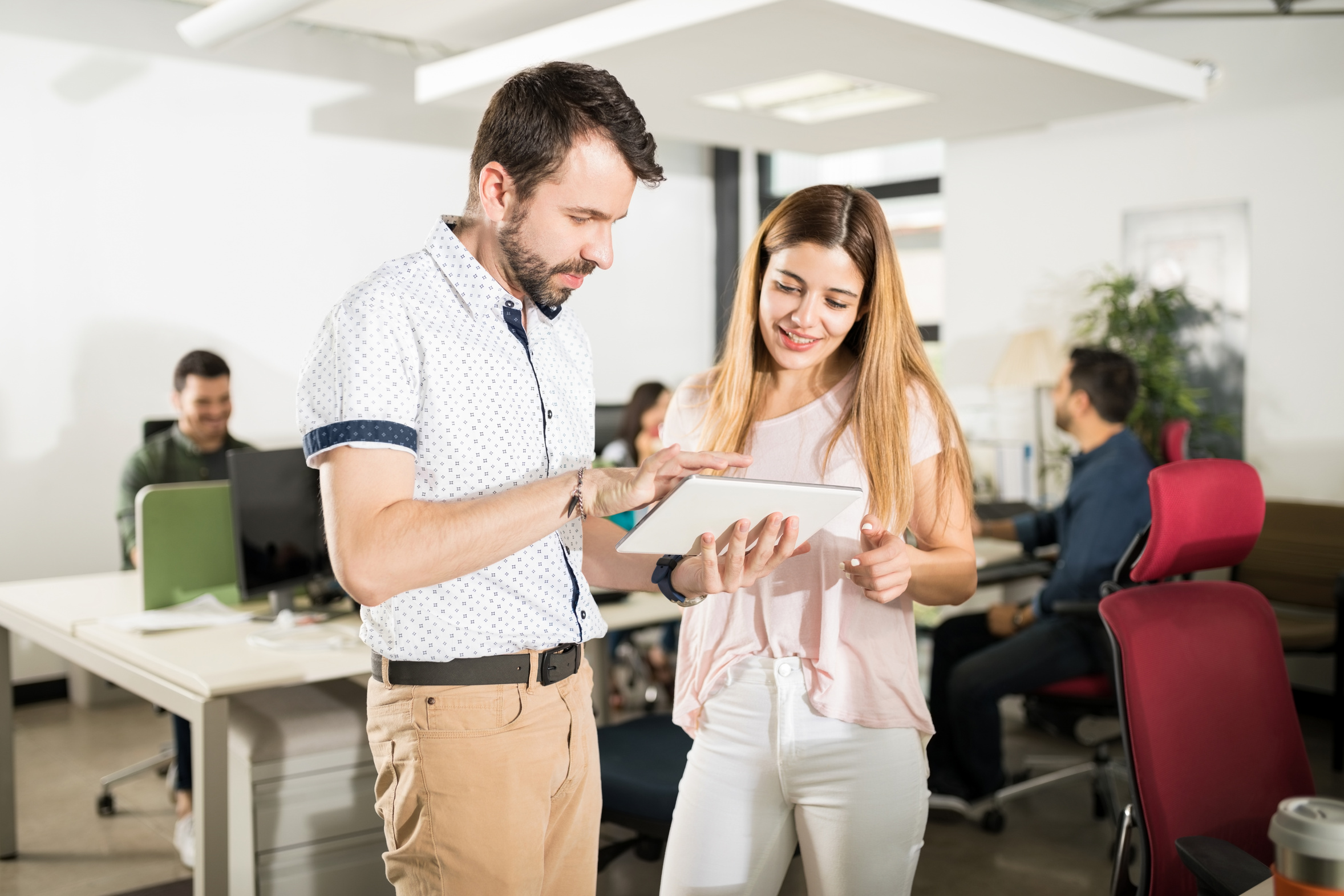 Experienced colleague helping a new employee at her computer, the kind of desk-side help a growing office relies on
