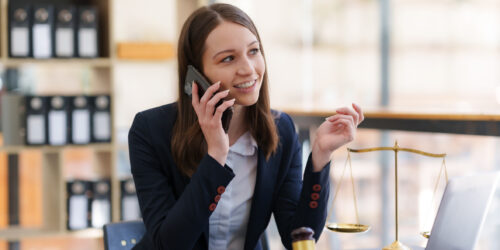 Lawyer on a phone call at her desk with case files open, representing a law firm reaching a named IT contact who already knows the firm