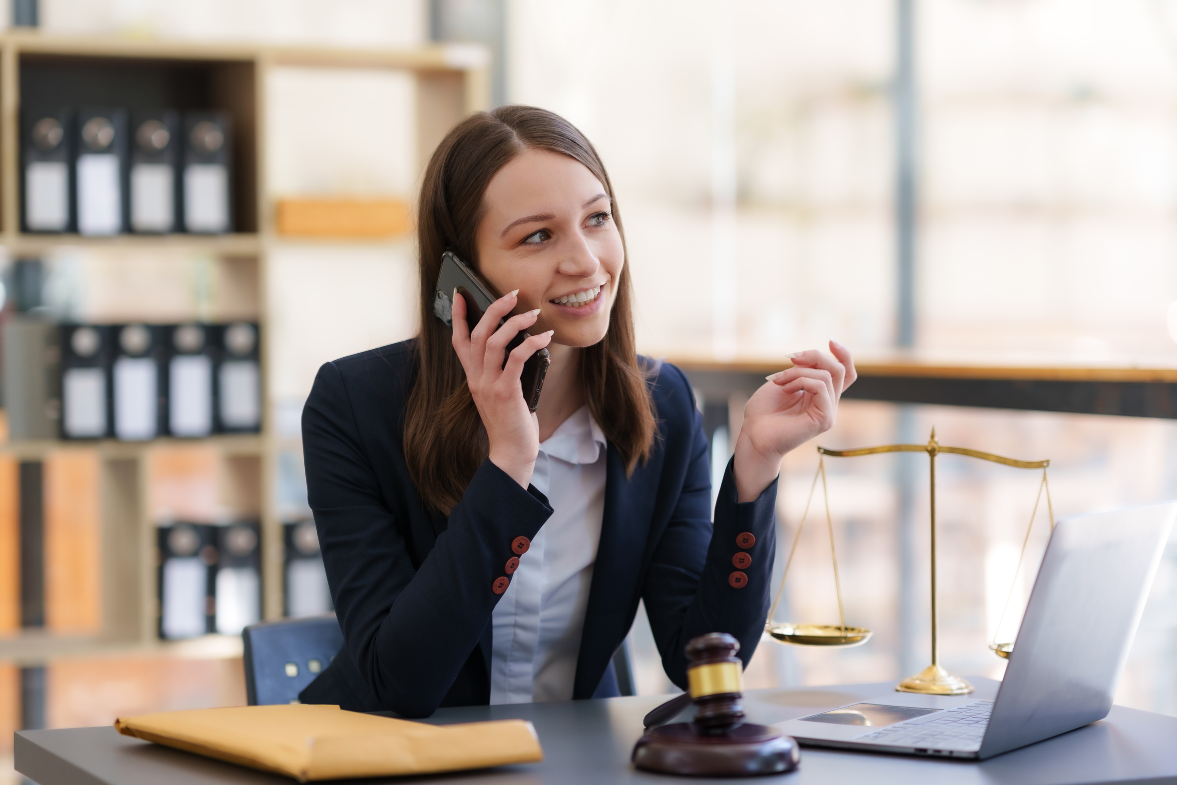 Lawyer on a phone call at her desk with case files open, representing a law firm reaching a named IT contact who already knows the firm