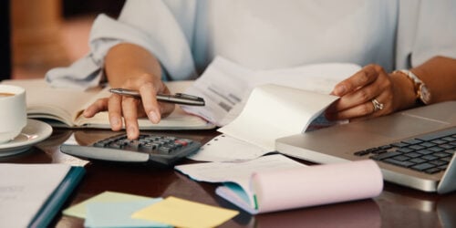 Small business owner working through bills and service paperwork at her desk, checking what an IT support contract actually covers