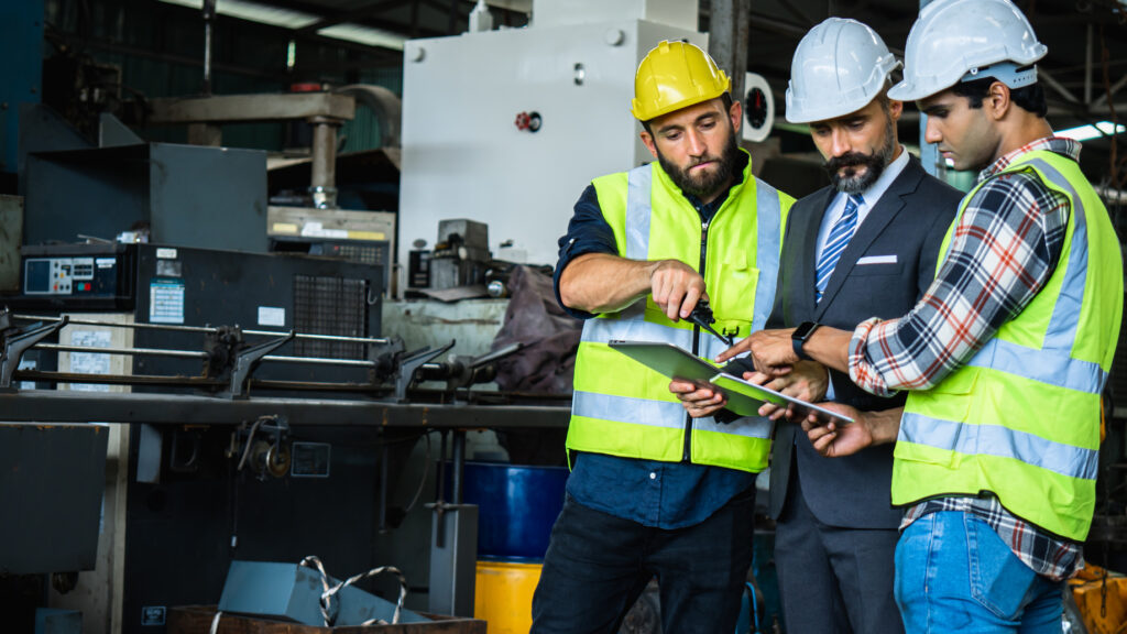 Plant manager and engineers discussing a production plan on the factory floor, the kind of planning a vCIO ties technology to